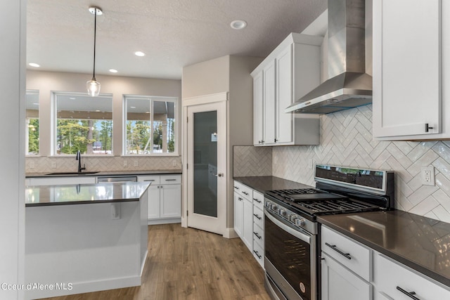 kitchen featuring backsplash, gas stove, wall chimney exhaust hood, and light wood-type flooring