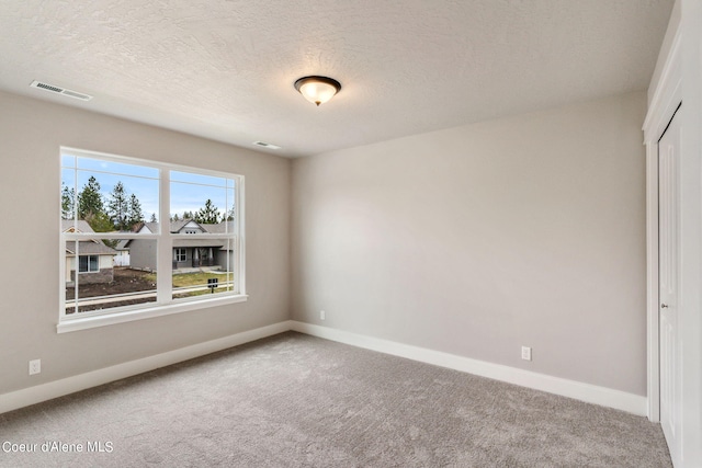 spare room with carpet and a textured ceiling