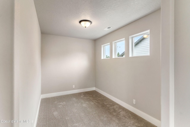 carpeted empty room featuring a textured ceiling