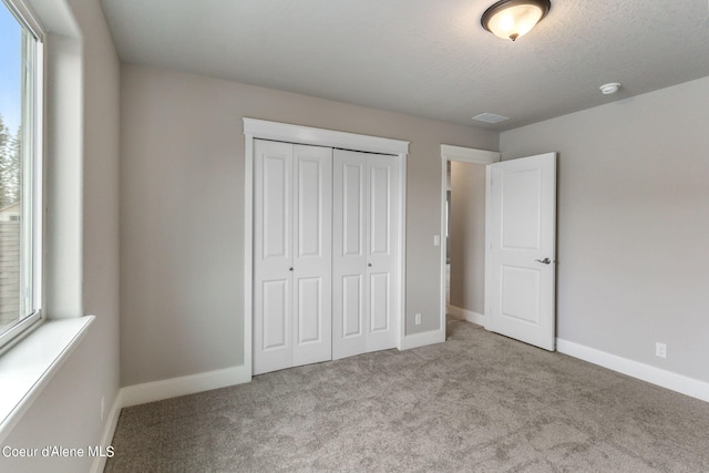 unfurnished bedroom featuring a textured ceiling, a closet, and carpet floors