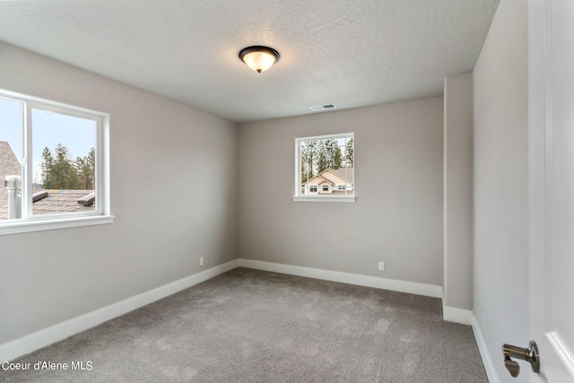 carpeted empty room featuring a textured ceiling