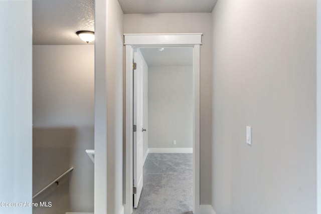 hallway featuring a textured ceiling and carpet flooring