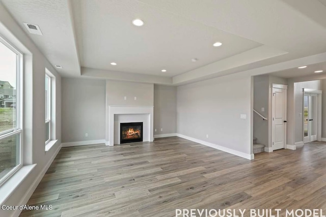 unfurnished living room with hardwood / wood-style floors and a raised ceiling