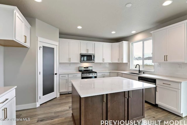 kitchen with appliances with stainless steel finishes, sink, hardwood / wood-style flooring, and tasteful backsplash