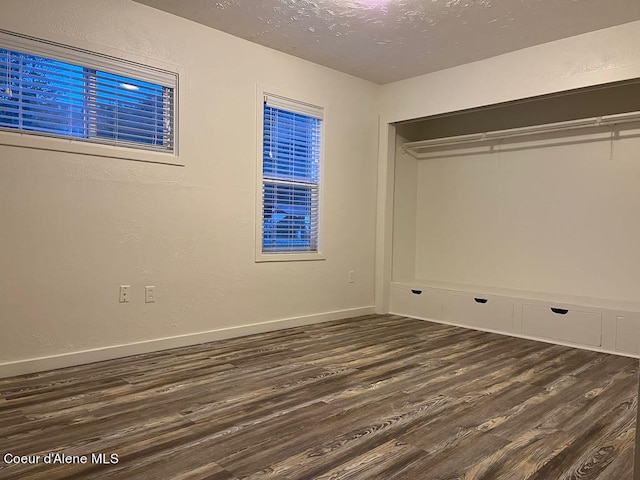 unfurnished bedroom with dark wood-type flooring and a closet