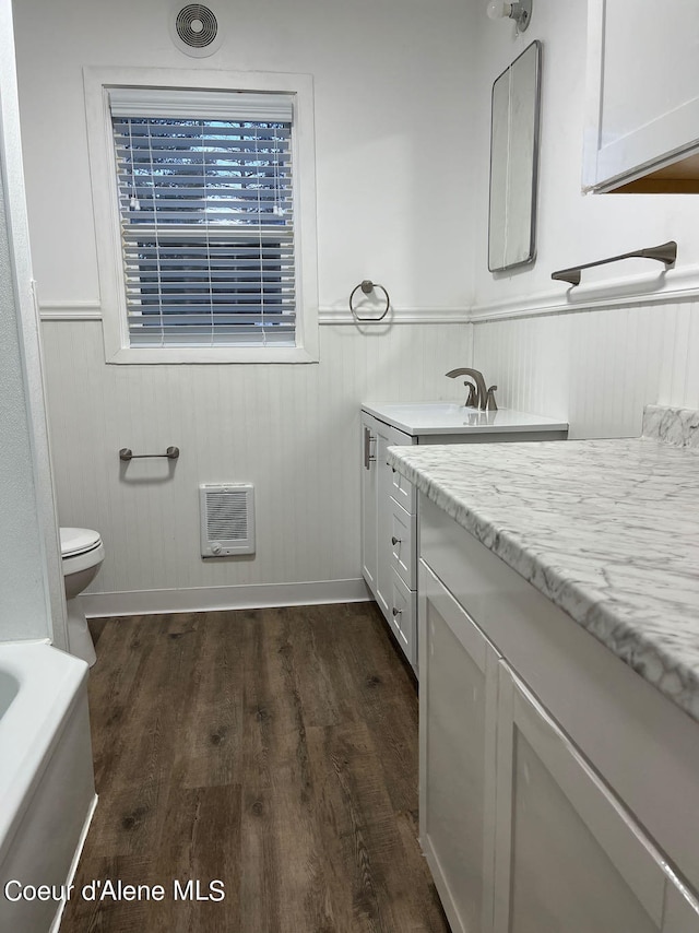 bathroom featuring vanity with extensive cabinet space, toilet, and hardwood / wood-style flooring