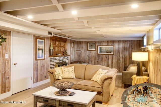 living room with wood walls, light wood-type flooring, and a brick fireplace