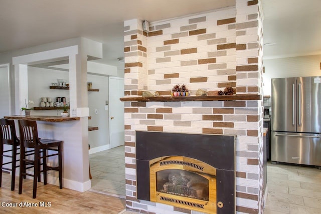 interior space featuring tile patterned floors, a fireplace, and stainless steel refrigerator