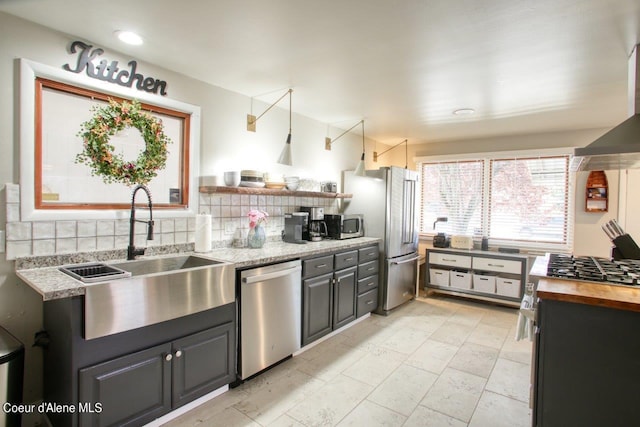 kitchen featuring stainless steel appliances, wooden counters, backsplash, light tile patterned floors, and sink