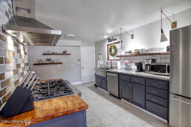 kitchen featuring light tile patterned floors, appliances with stainless steel finishes, sink, backsplash, and wall chimney range hood