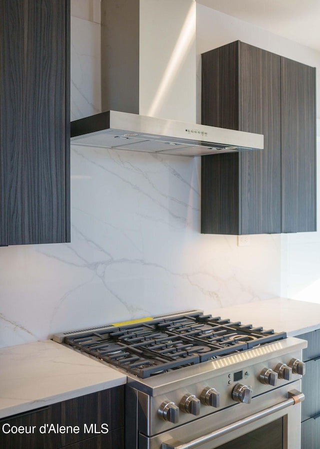 kitchen with high end range, wall chimney range hood, and decorative backsplash