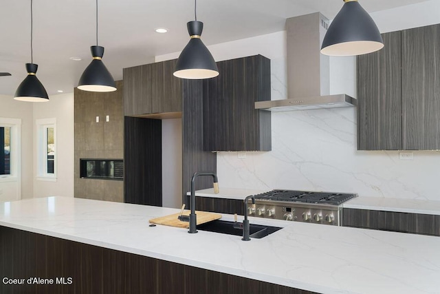 kitchen with decorative backsplash, sink, wall chimney exhaust hood, and decorative light fixtures