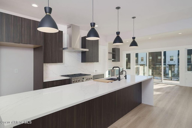 kitchen featuring decorative light fixtures, stainless steel gas cooktop, and wall chimney range hood