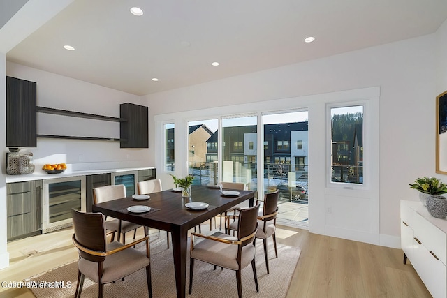 dining area with beverage cooler and light hardwood / wood-style flooring