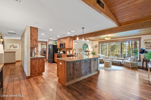 5718 E Sleepy Ln, Coeur Dalene, ID 83814 - kitchen featuring stainless steel microwave, a peninsula, light stone countertops, light wood-style floors, and freestanding refrigerator