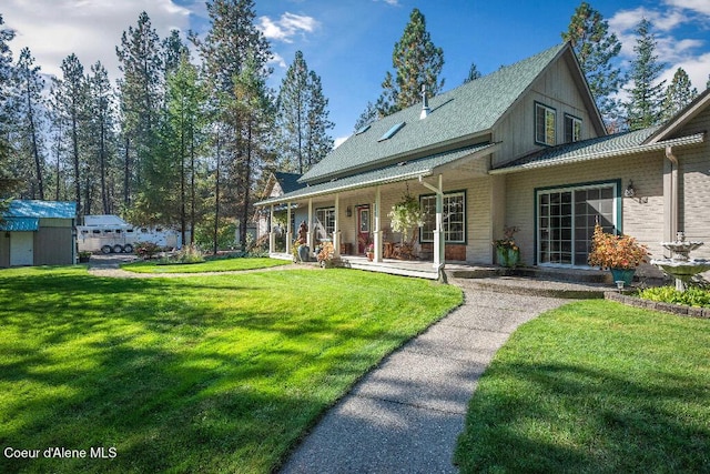 back of house with covered porch, an outbuilding, a garage, and a lawn