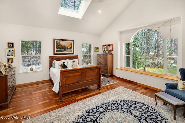 bedroom with vaulted ceiling with skylight and hardwood / wood-style floors