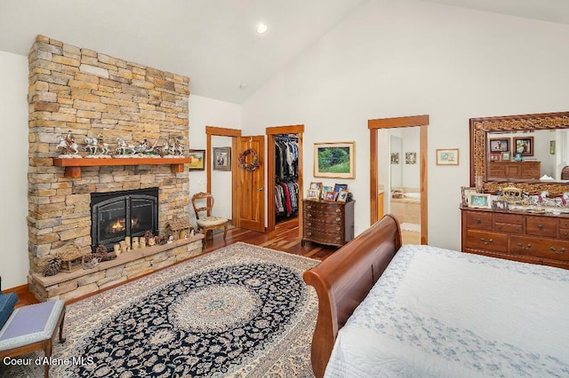 bedroom featuring a fireplace, hardwood / wood-style flooring, a spacious closet, high vaulted ceiling, and a closet