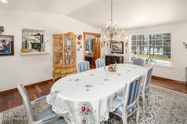 dining space with wood-type flooring, a notable chandelier, and vaulted ceiling