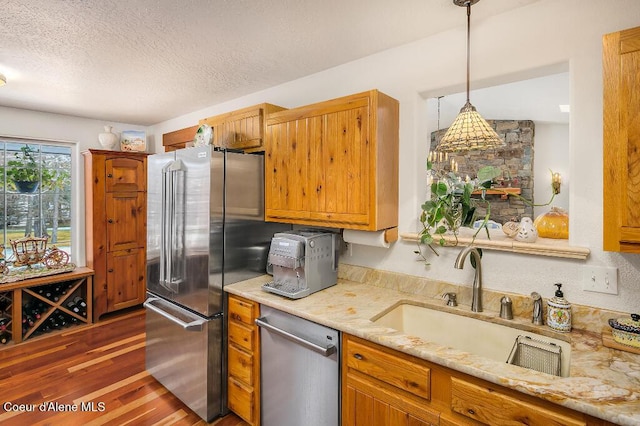 kitchen featuring sink, hanging light fixtures, appliances with stainless steel finishes, dark wood-type flooring, and a textured ceiling