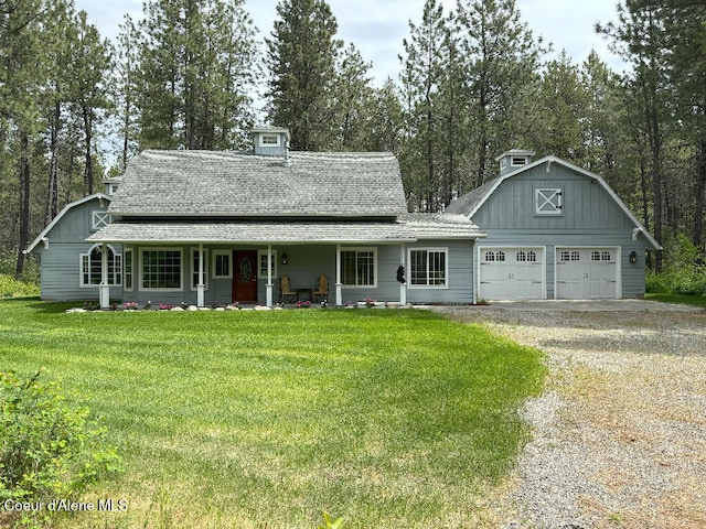 view of front of house featuring covered porch, a front lawn, and a garage