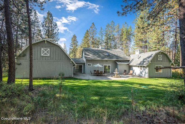 back of house featuring a patio area, an outbuilding, and a yard