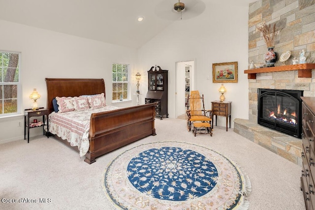 carpeted bedroom featuring ceiling fan, multiple windows, lofted ceiling, and a fireplace