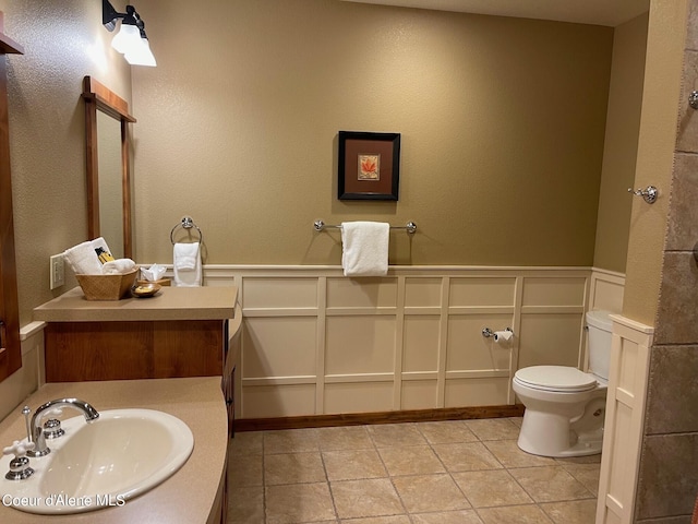 bathroom with tile flooring, toilet, and vanity