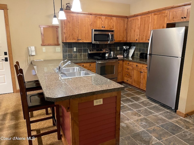 kitchen with tasteful backsplash, a breakfast bar area, appliances with stainless steel finishes, sink, and pendant lighting