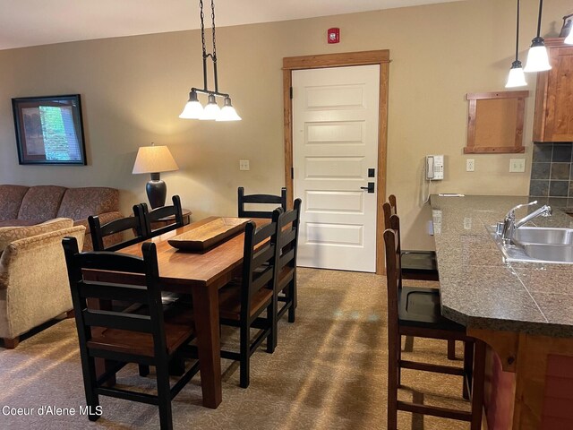 carpeted dining space with sink and a chandelier