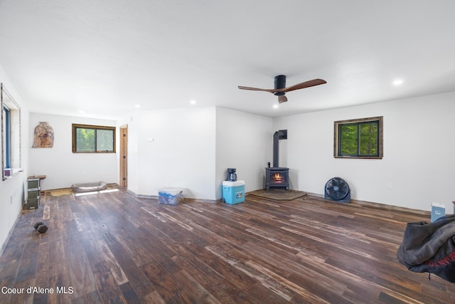 unfurnished living room featuring a ceiling fan, wood finished floors, a wood stove, and recessed lighting