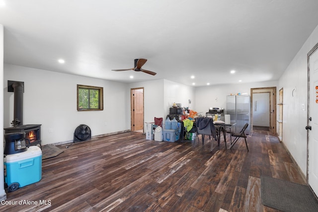 living area featuring a wood stove, a ceiling fan, wood finished floors, and recessed lighting