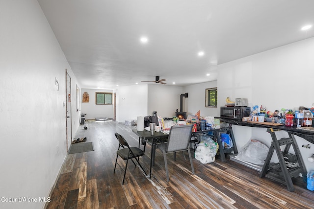 dining space with recessed lighting, wood finished floors, a wood stove, and a healthy amount of sunlight