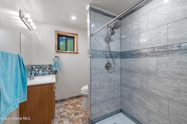 full bath featuring toilet, a tile shower, and vanity