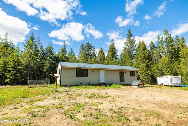 back of property with an outbuilding, crawl space, and metal roof