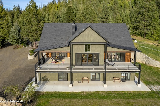 rear view of house featuring a patio area, a lawn, and stucco siding