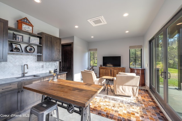 kitchen featuring a breakfast bar area, dark brown cabinetry, recessed lighting, a sink, and tasteful backsplash