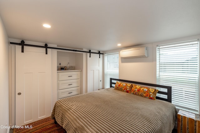 bedroom with a wall unit AC, a barn door, multiple windows, and recessed lighting