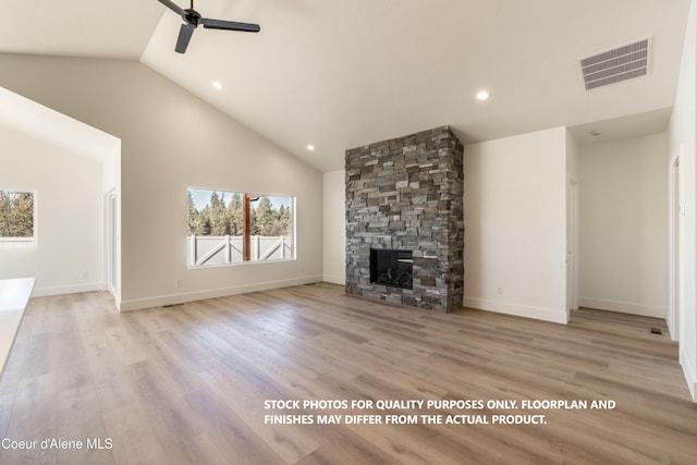 unfurnished living room with a stone fireplace, light wood-type flooring, high vaulted ceiling, and ceiling fan