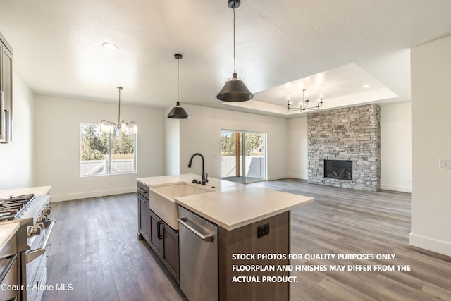 kitchen featuring sink, an inviting chandelier, an island with sink, pendant lighting, and stainless steel appliances