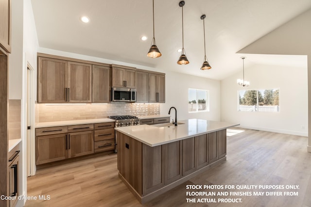 kitchen with decorative light fixtures, lofted ceiling, sink, backsplash, and a center island with sink