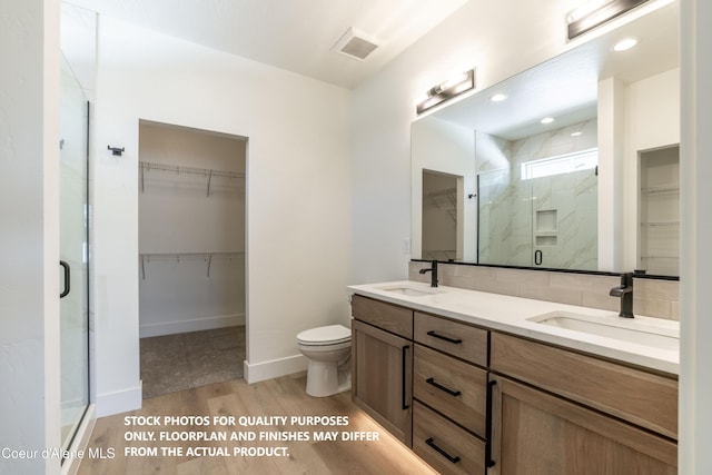 bathroom featuring a shower with door, vanity, hardwood / wood-style flooring, and toilet