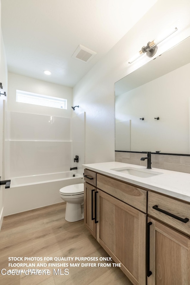 full bathroom with shower / bathing tub combination, vanity, hardwood / wood-style floors, and toilet