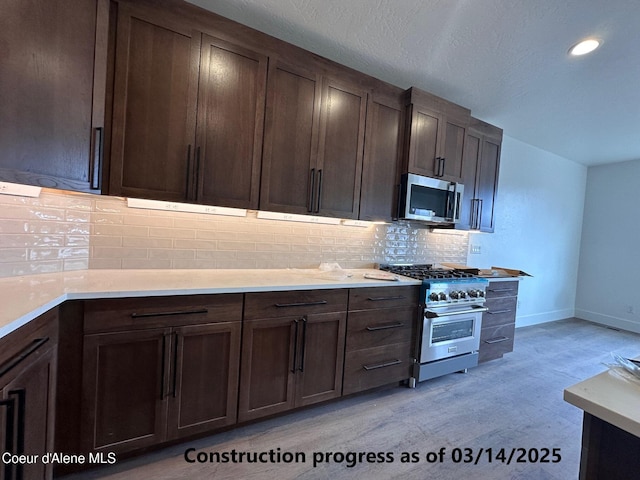 kitchen with tasteful backsplash, appliances with stainless steel finishes, light countertops, baseboards, and dark brown cabinets