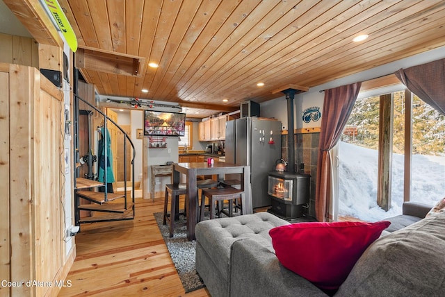 living room featuring light hardwood / wood-style floors, a wood stove, and wood ceiling