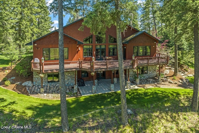 rear view of house featuring a deck, a lawn, and a patio area