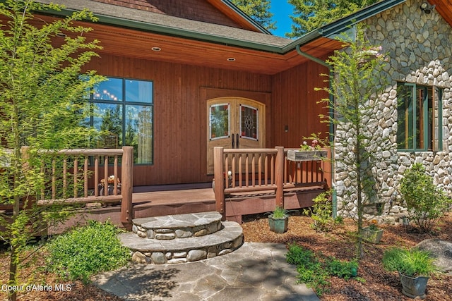 property entrance with a deck and stone siding