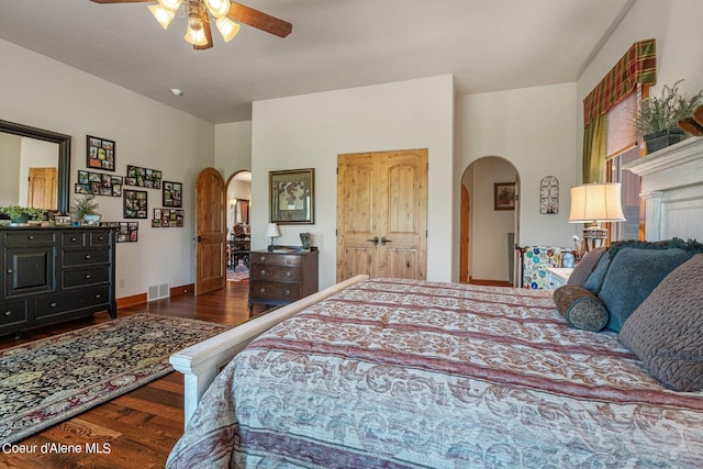 bedroom with arched walkways, a ceiling fan, visible vents, wood finished floors, and baseboards