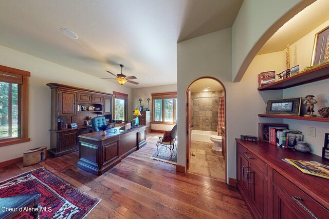 office featuring arched walkways, dark wood-style floors, baseboards, and a ceiling fan