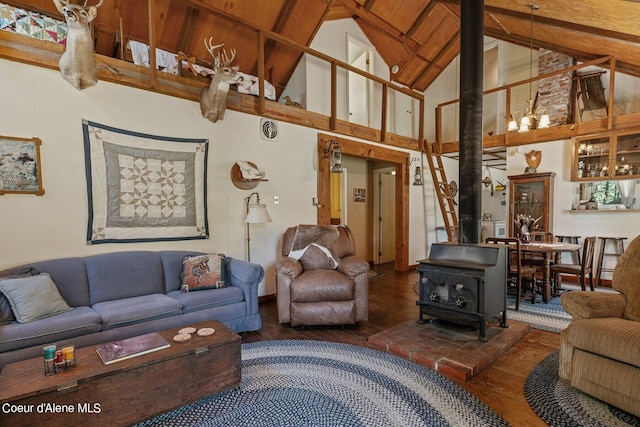 living room featuring wood finished floors, a wood stove, beam ceiling, and high vaulted ceiling